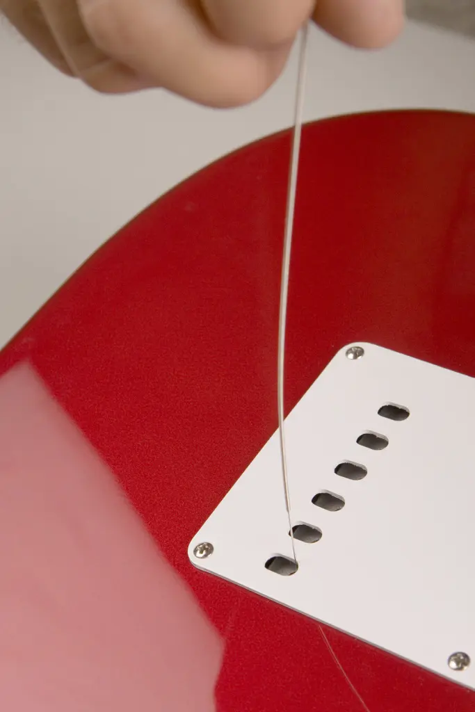 Infila le corde dal retro della chitarra nel caso di una strato