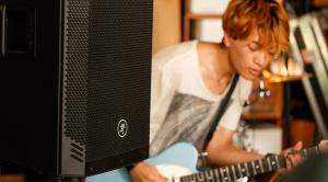Cassa amplificata Mackie Thrashv2 accanto a un chitarrista in sala prove